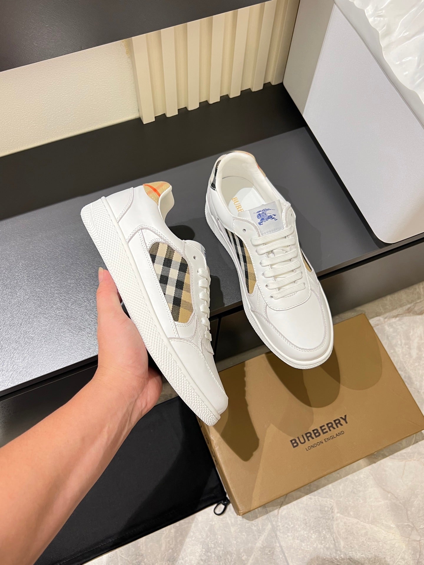 White Burberry check lace-up sneakers, side view held in hand