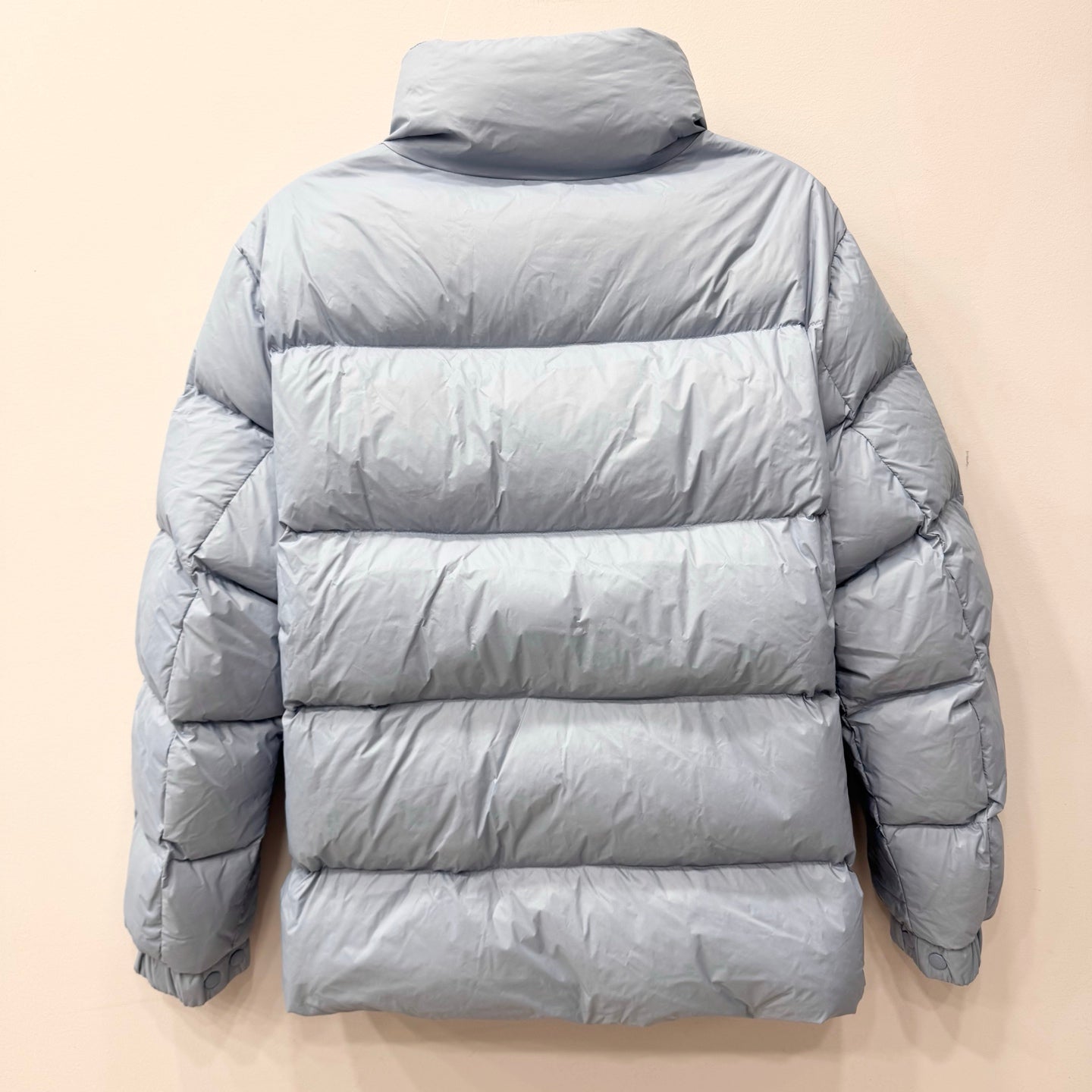 Light blue long puffer jacket back view with quilted panels and central zip