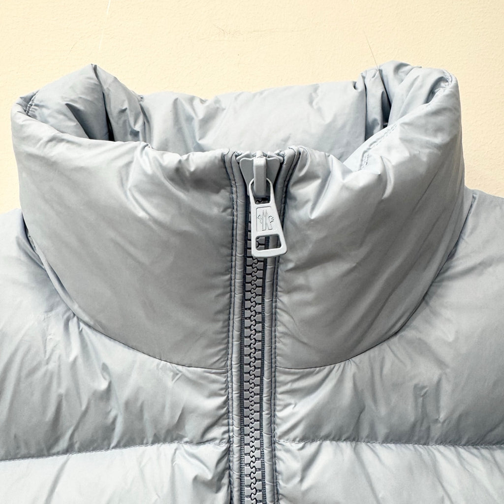 Light blue puffer jacket close-up with full-zip seam and quilted front sections