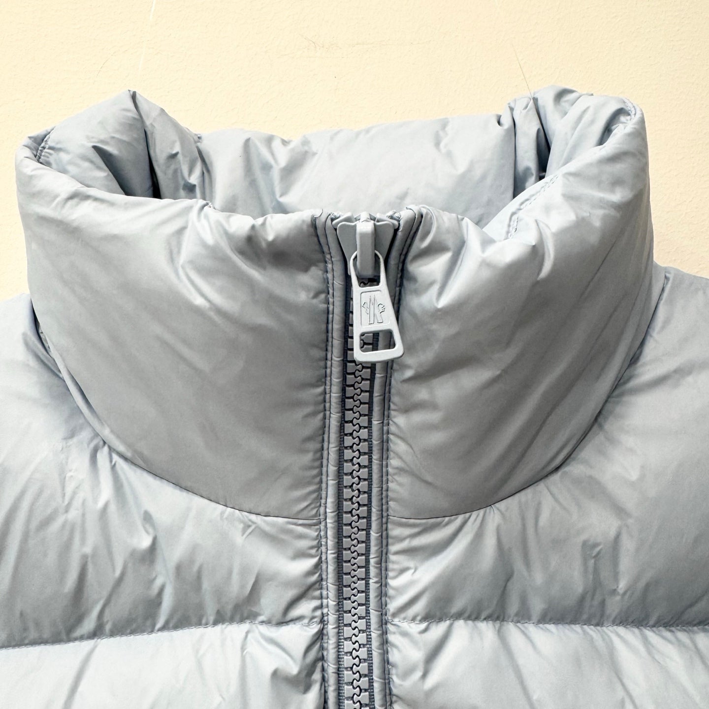 Light blue puffer jacket close-up with full-zip seam and quilted front sections