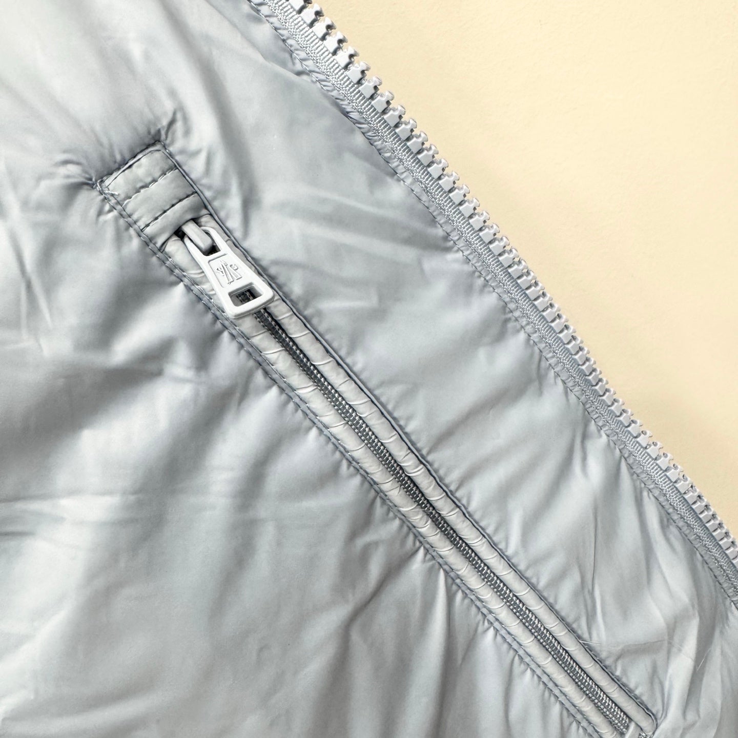 Light blue puffer jacket zipper placket with two zip pullers and stitching
