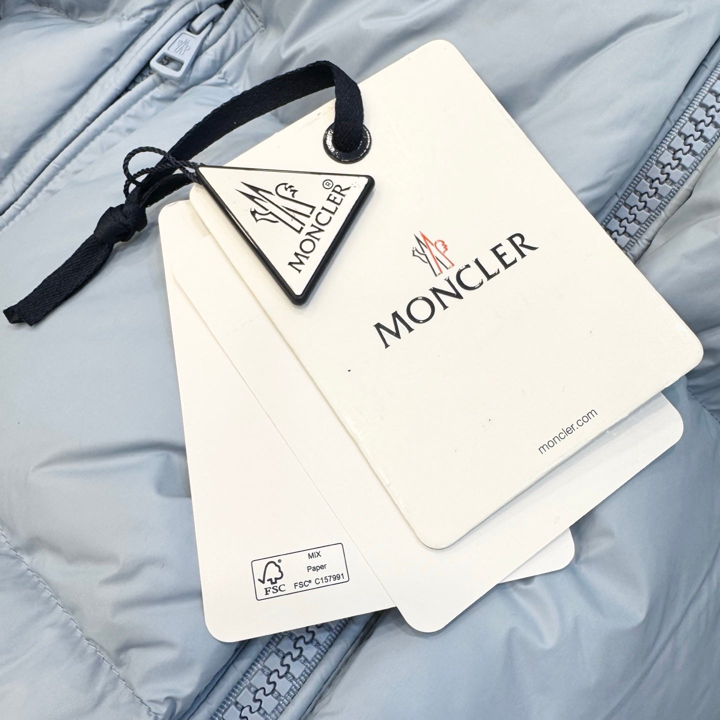 Light blue puffer jacket with hanging Moncler tags and retail label