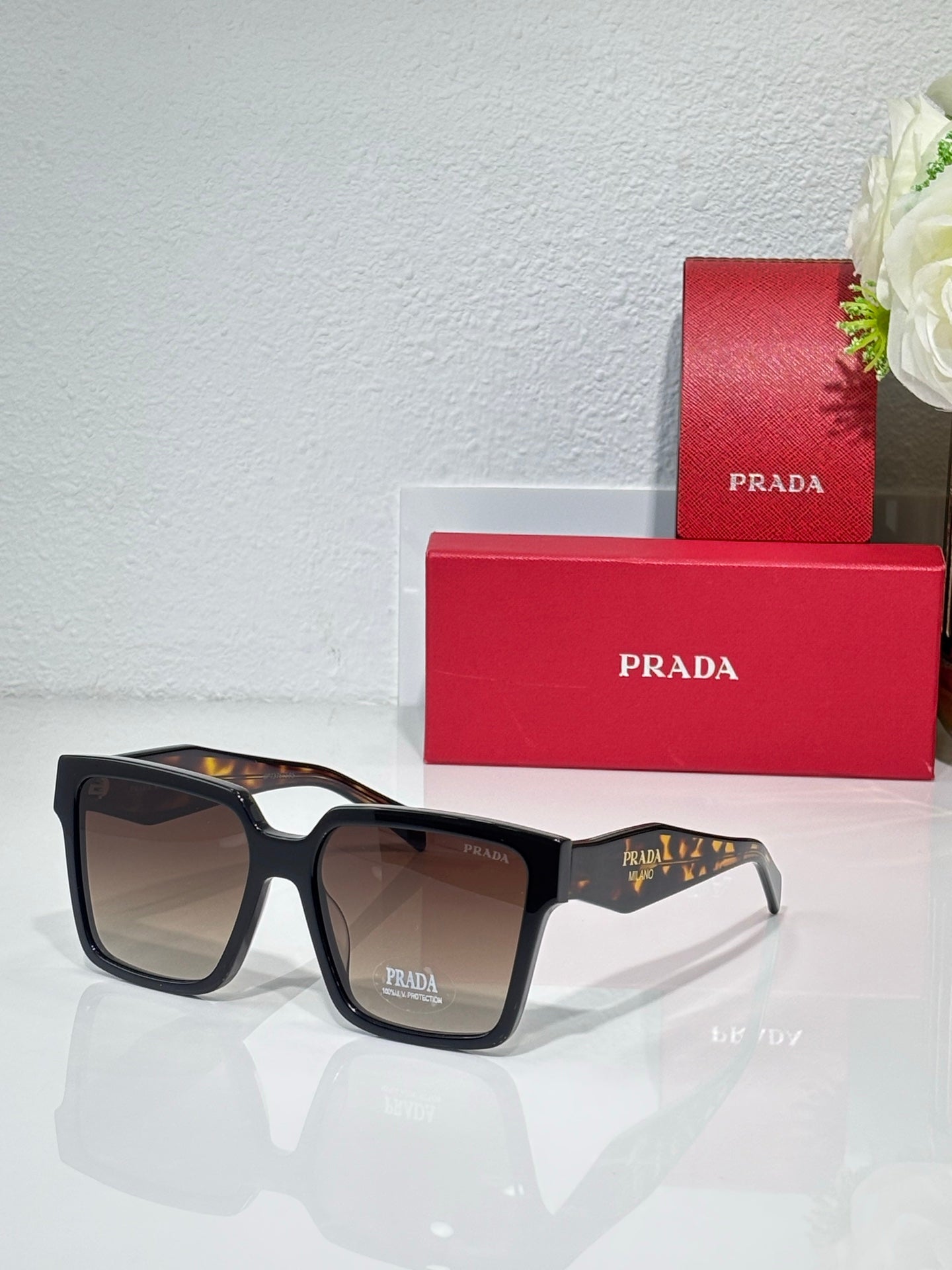Prada sunglasses with black frame and brown tortoise-style temples