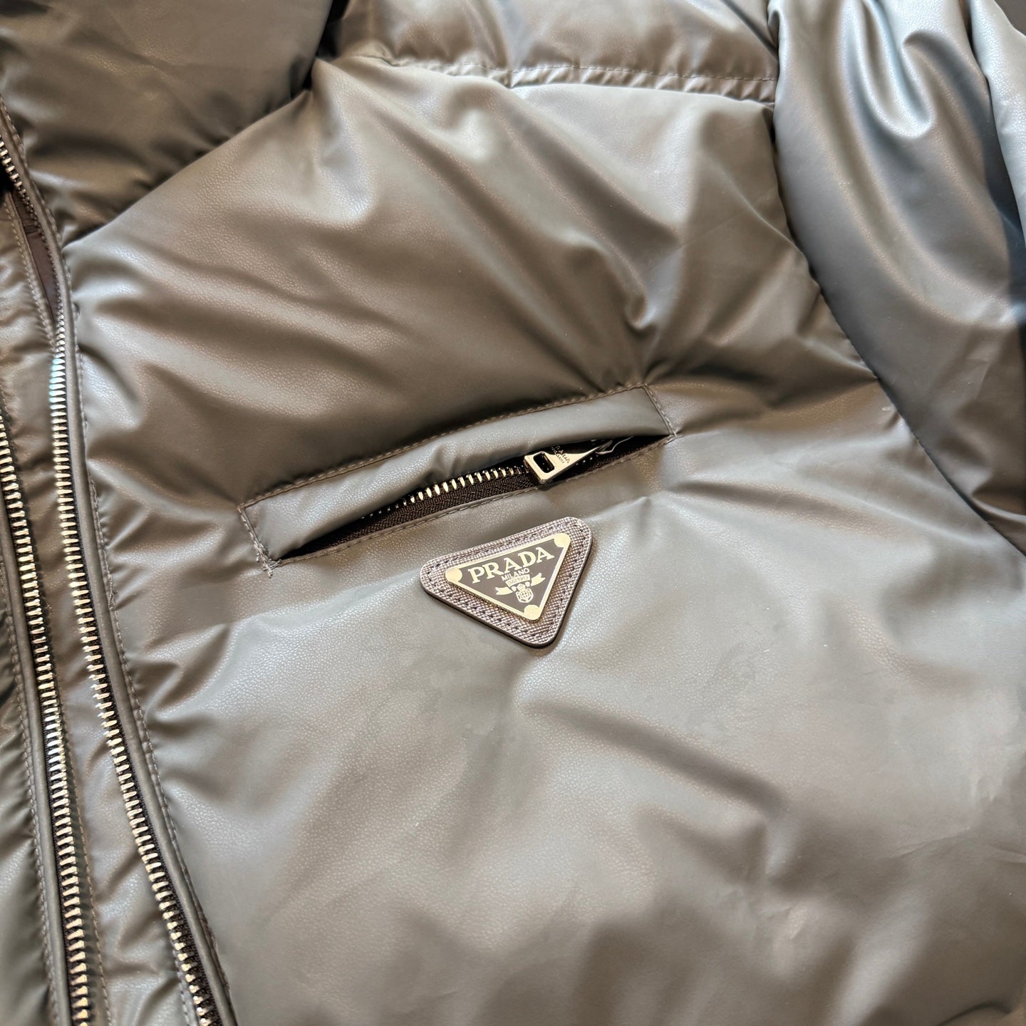 Prada puffer jacket chest logo patch on zipper placket, tan fabric
