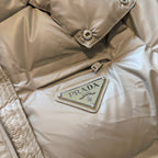 Beige puffer jacket with Prada logo patch on chest and metal zipper trim