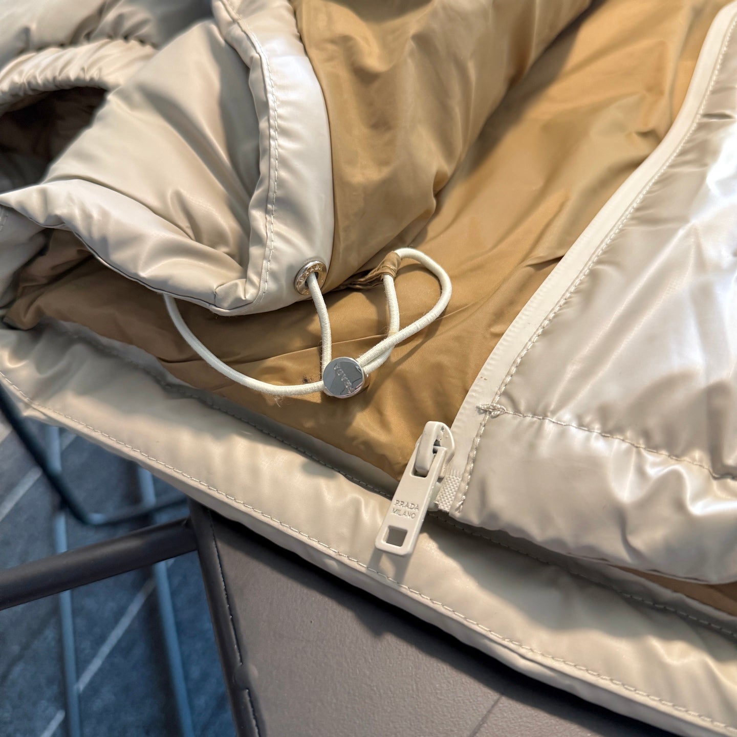 Beige hooded puffer jacket with white drawstring and cord lock at hem