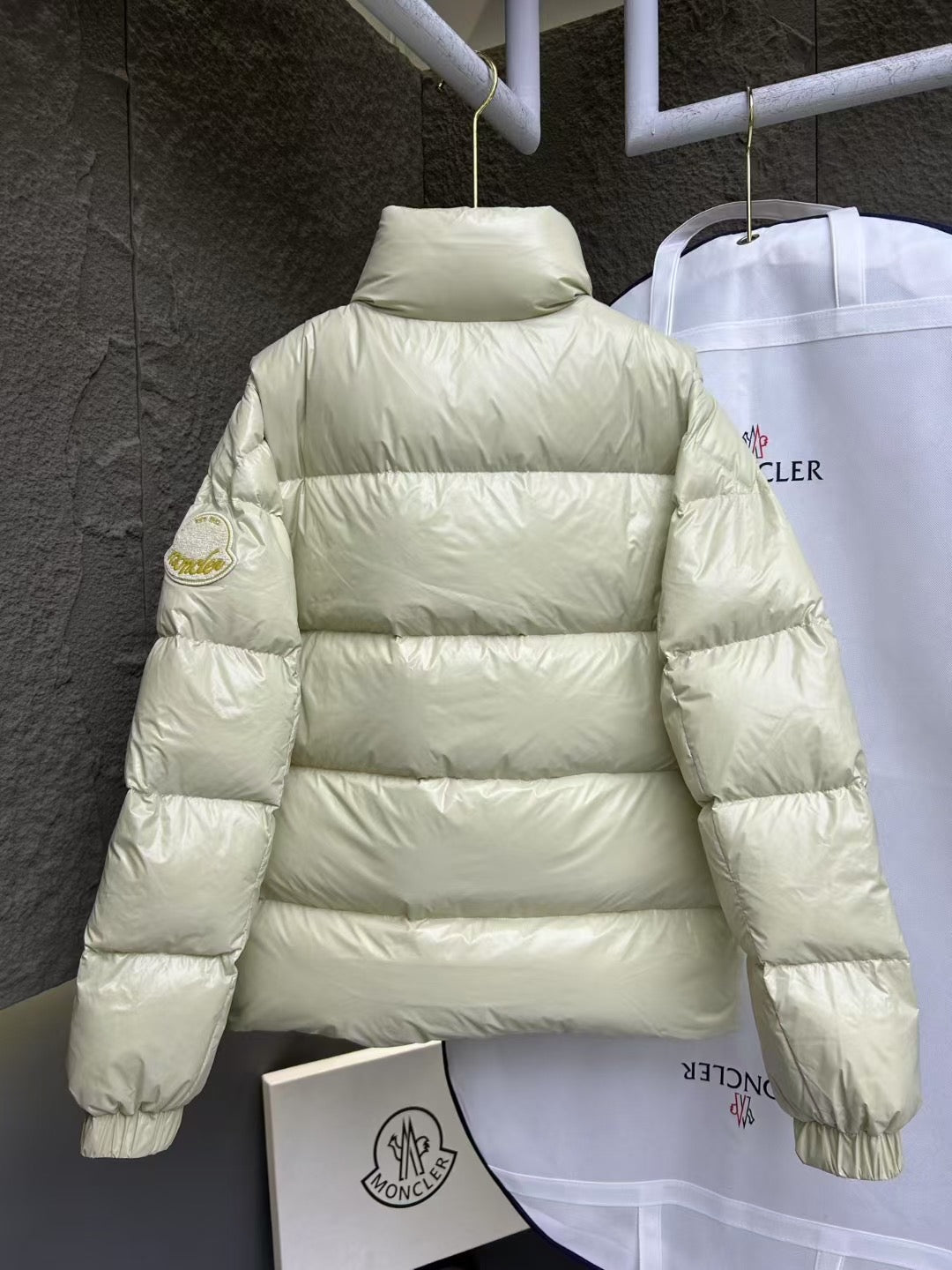 Cream puffer jacket back view with high neck and horizontal quilted stripes.