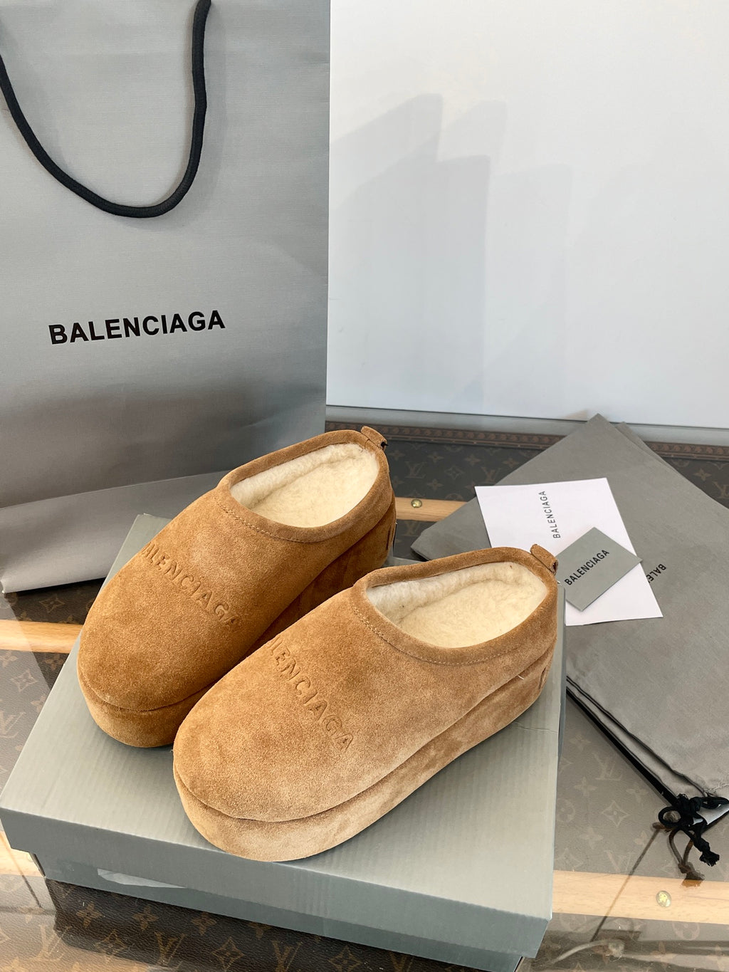 Tan suede slip-on sandals with beige lining and BALENCIAGA detail, front view on box.