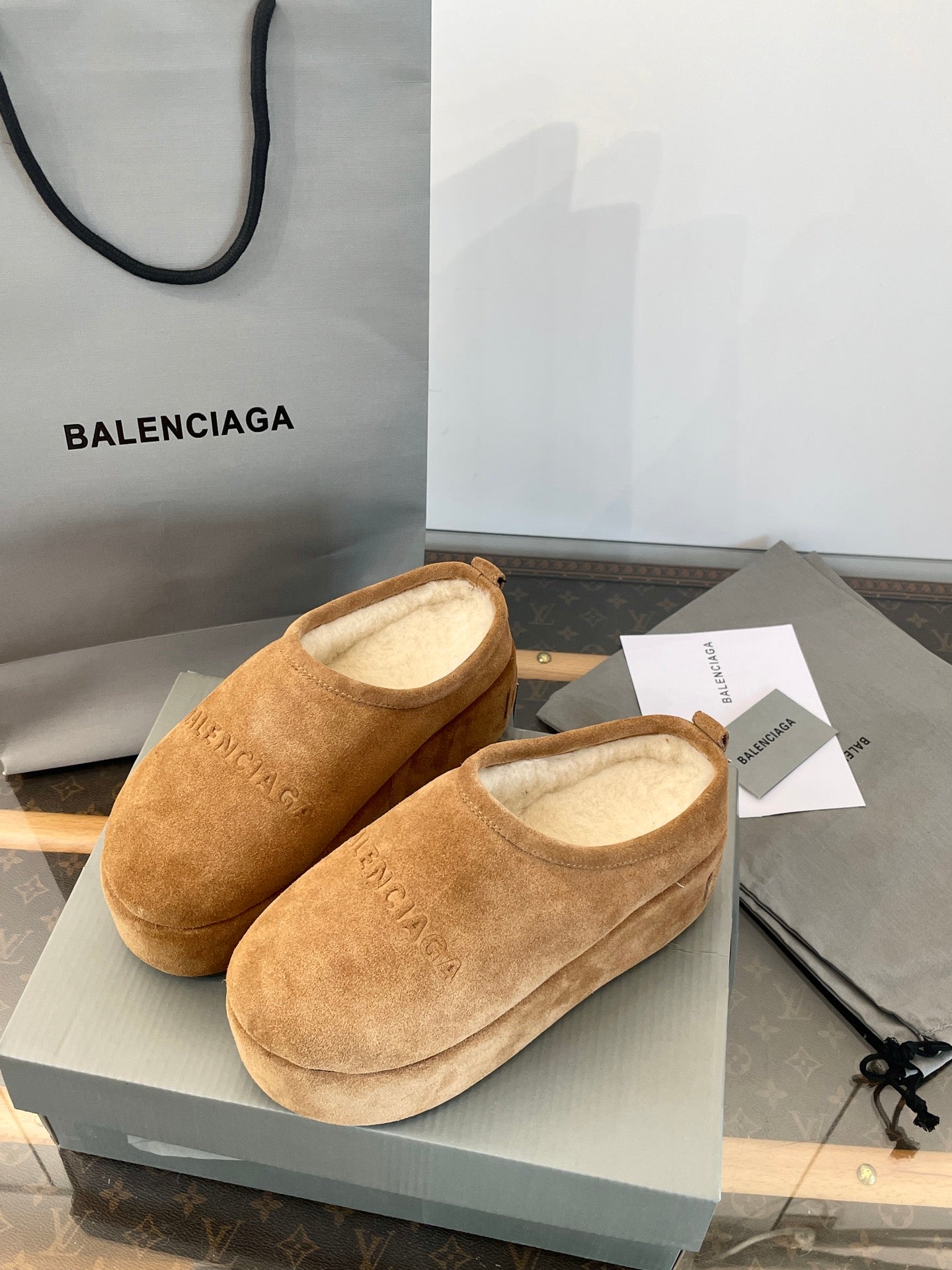 Tan suede slip-on sandals with beige lining and BALENCIAGA detail, front view on box.