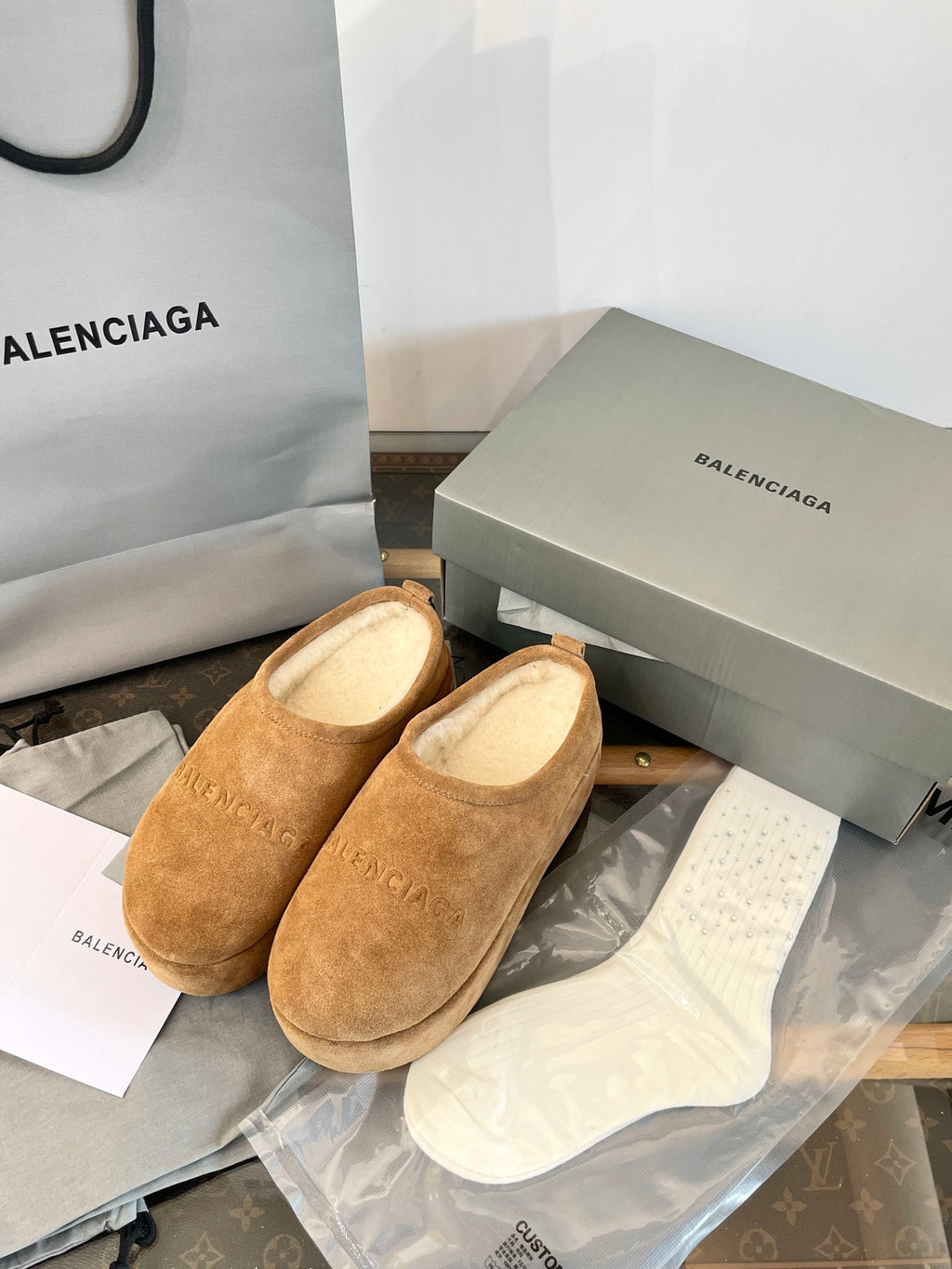 Tan suede slip-on sandals with beige lining, placed in a shoebox with tissue paper.
