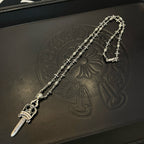 Silver-tone sword pendant necklace with ornate floral chain on a dark box