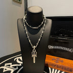 Silver-tone layered necklace with small cross charm and pendant sword, floral links