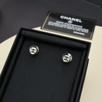 Silver-tone stud earrings with circular CC logo, displayed in a black box.