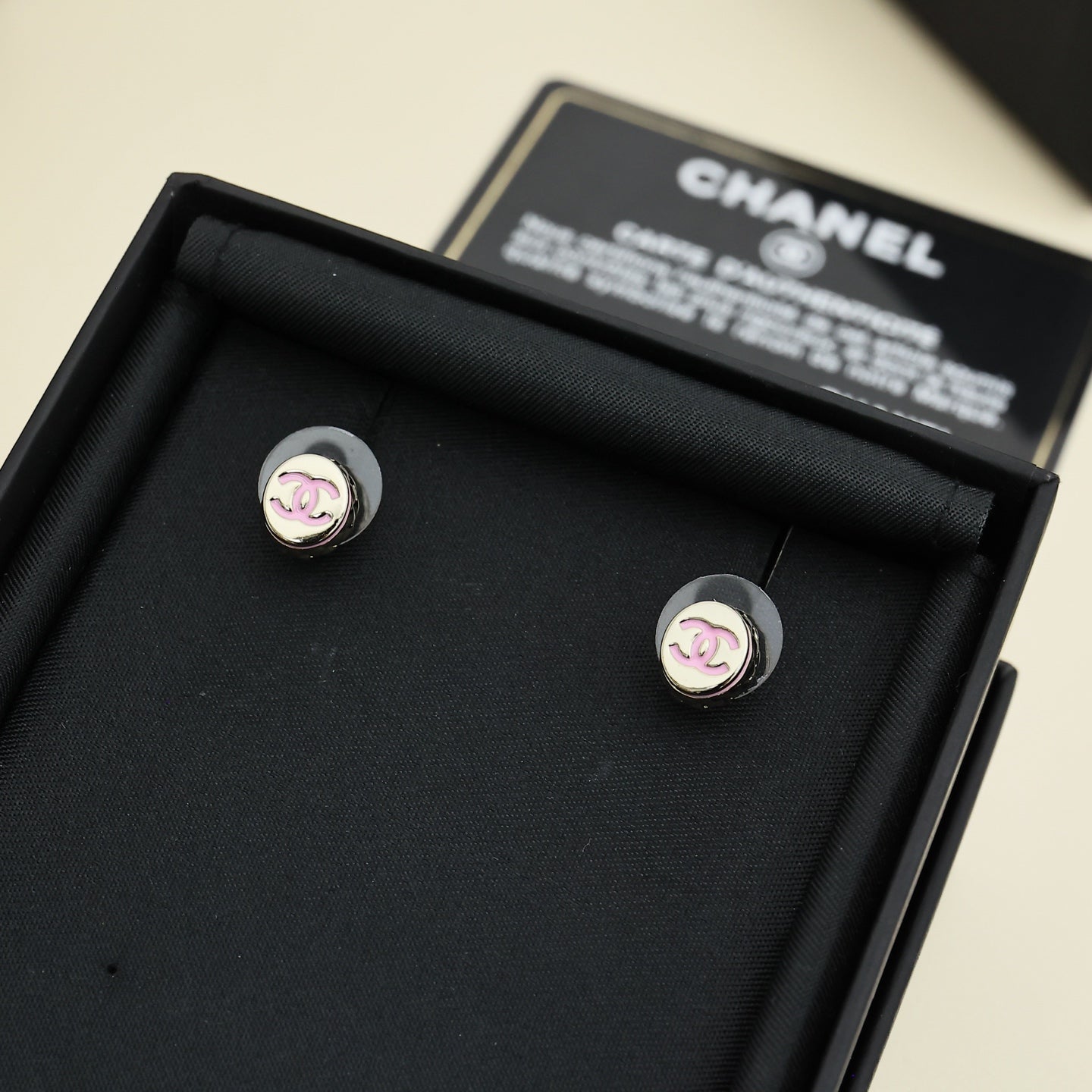 Silver-tone stud earrings with circular CC logo, shown in black earring tray.