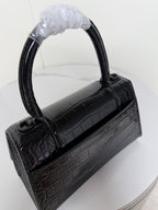 Black croc-texture strap with oval rings and clasp hardware for a mini handbag