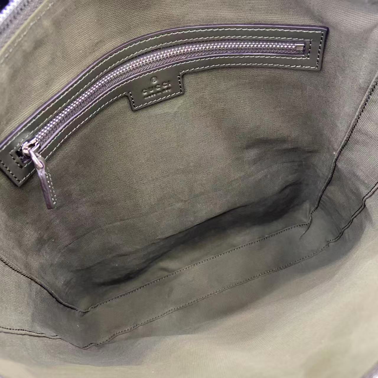 Gucci bag interior pocket close-up with stitched leather trim and zipper edge