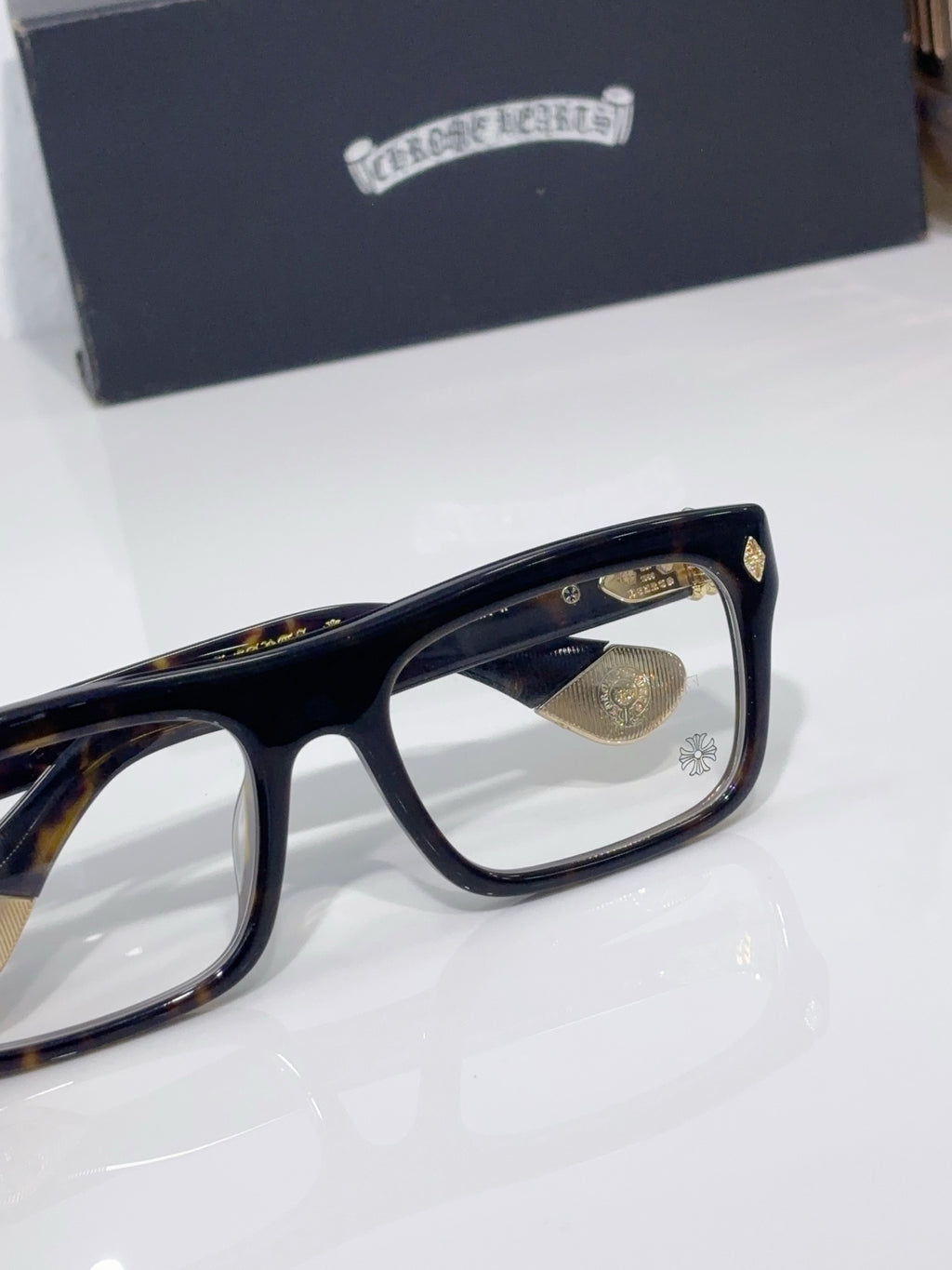 Side view of rectangular eyeglasses with dark frames and gold temple emblem