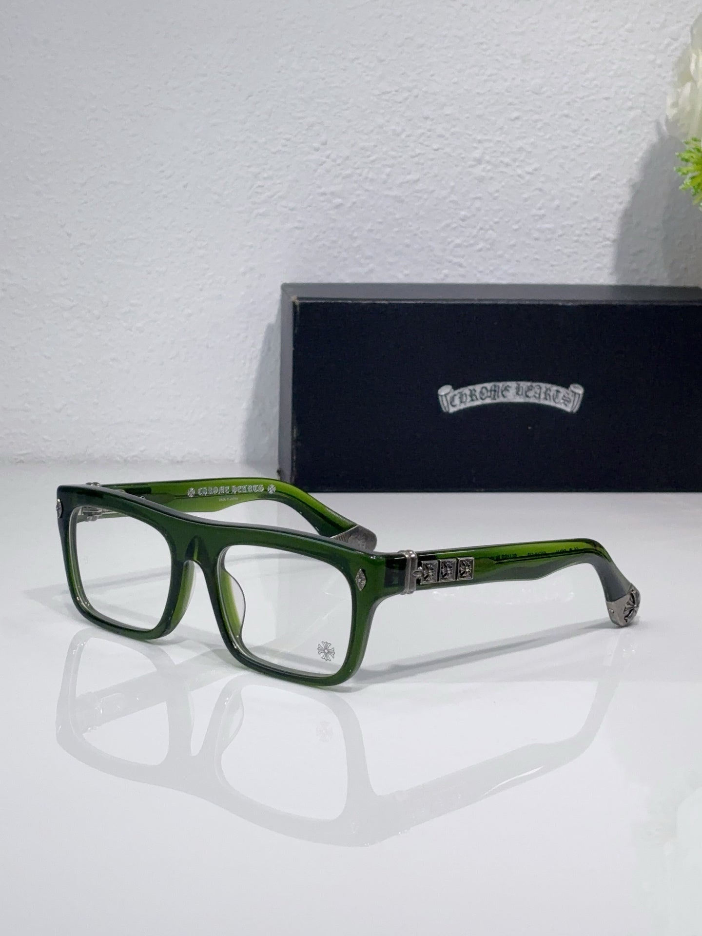 Rectangular eyeglasses with green frames and silver hinge with dark temple details