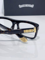 Close-up of rectangular eyeglasses with dark frames and gold hinge emblem