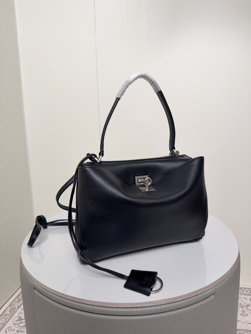 Dark leather handbag with top handle, strap ties, and front logo plaque