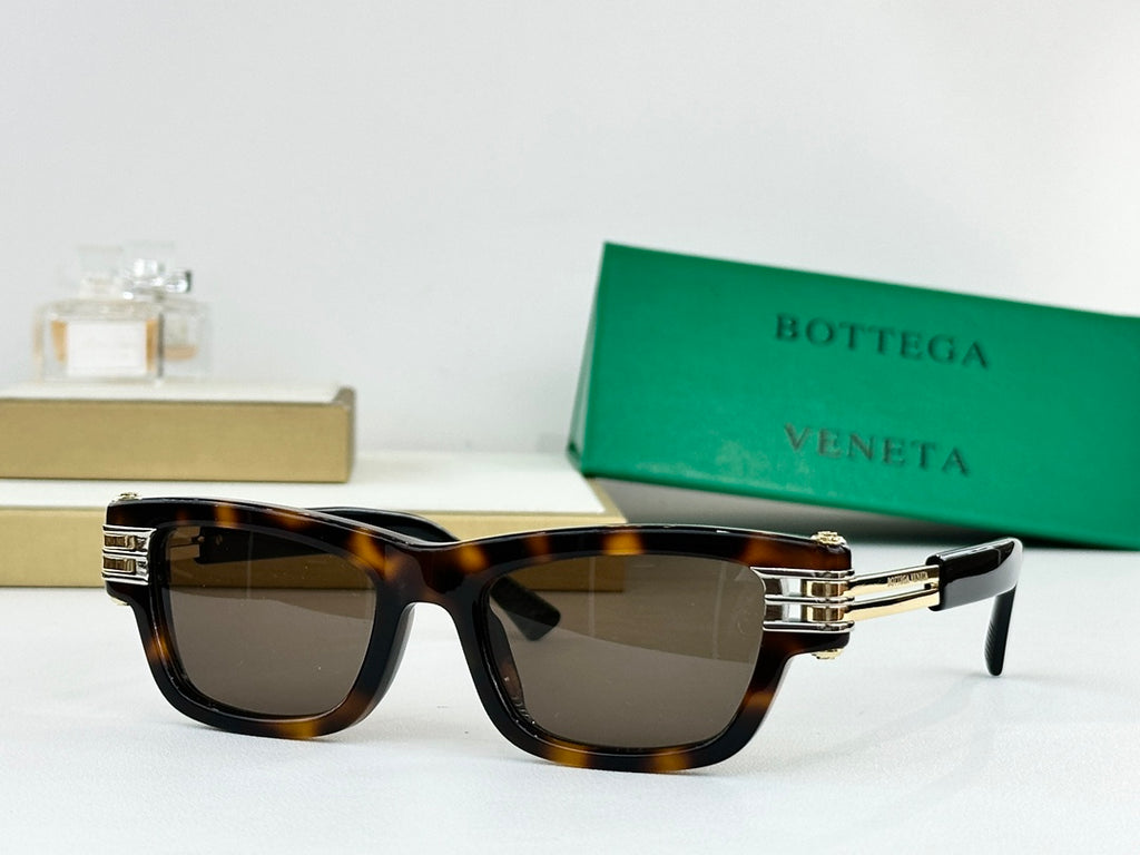 Tortoiseshell sunglasses with dark lenses and gold-tone metal hinge details.