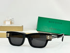 Black sunglasses with dark lenses and gold-tone metal accents on the temples.
