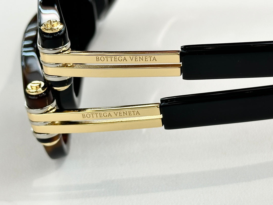 Sunglasses temple close-up with gold-tone metal bar and black end caps.