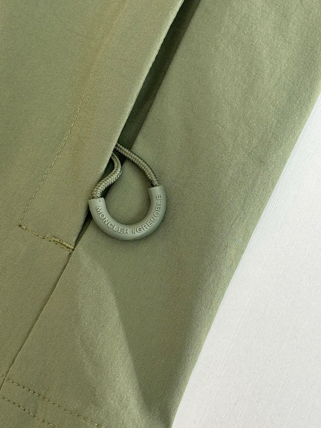 Moncler long jacket olive green with drawcord and small metal ring pull near hem