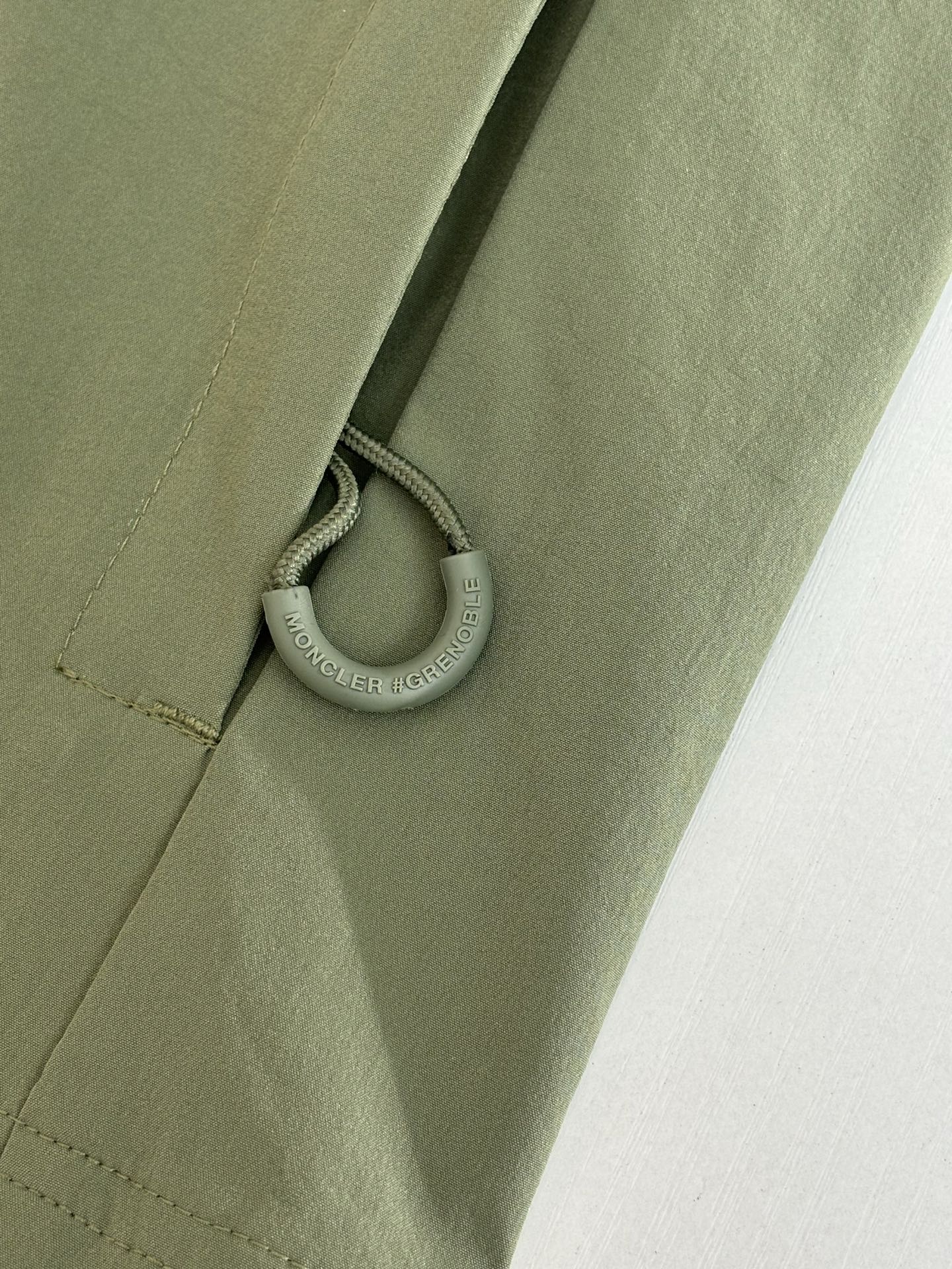 Moncler long jacket olive green with drawcord and small metal ring pull near hem