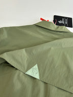 Long olive coat with hem label and triangular mesh underlayer