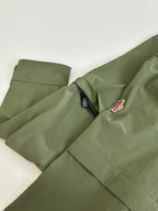 Long olive coat with snap front and red-and-white logo patch on chest