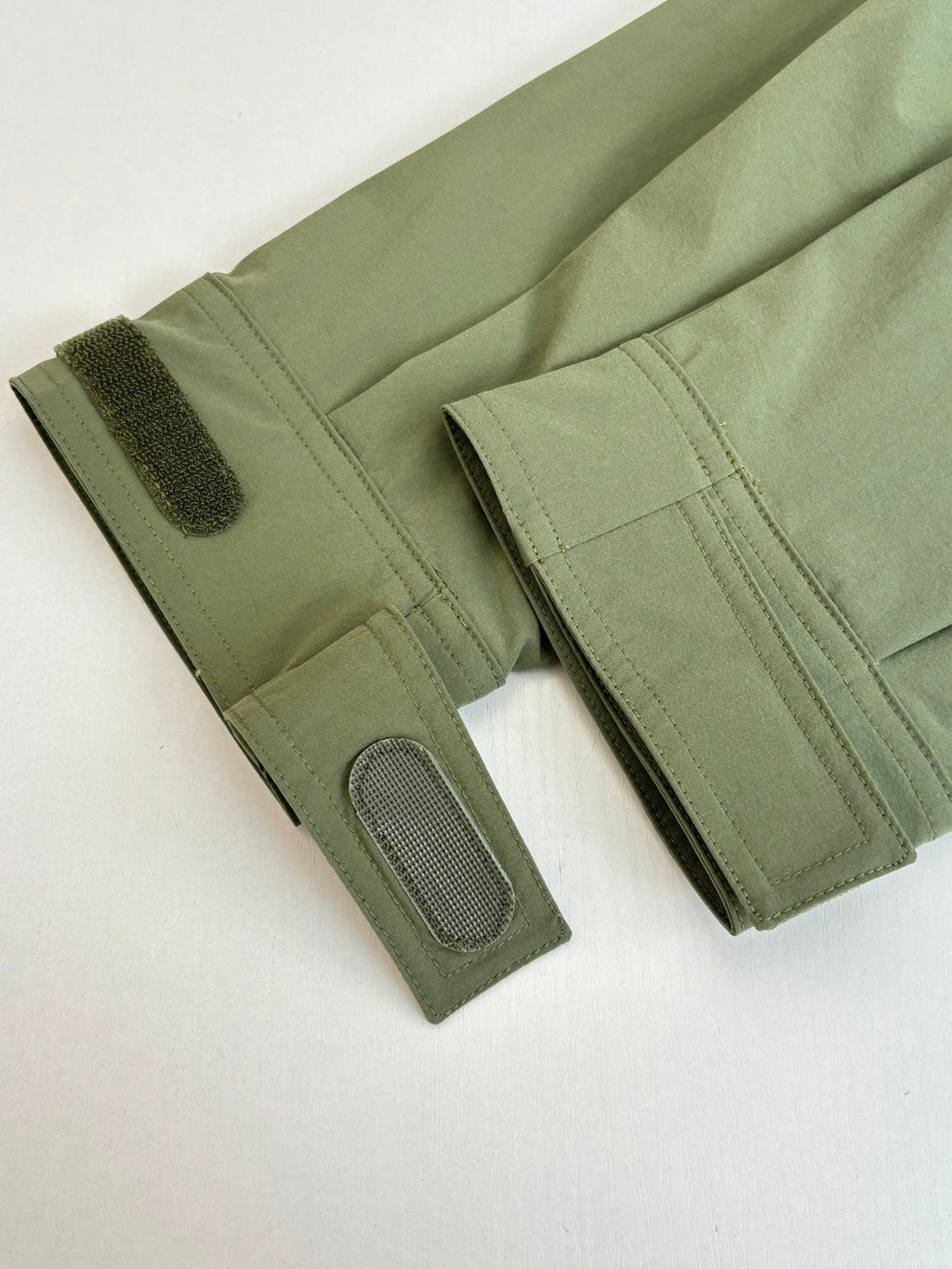 Long olive coat sleeves with textured cuffs and snap pocket detail