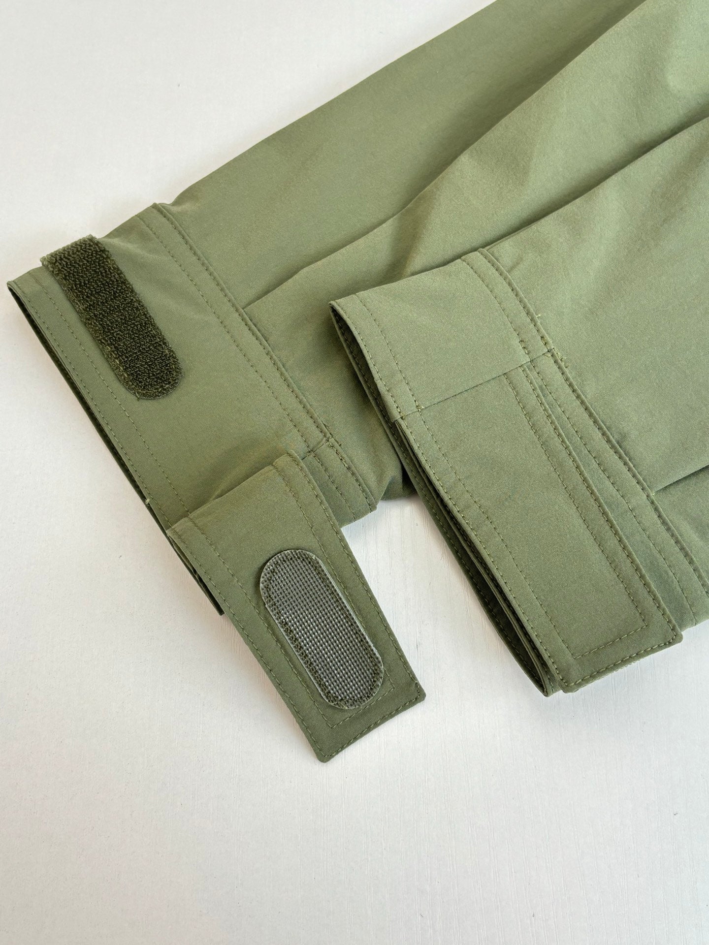 Long olive coat sleeves with textured cuffs and snap pocket detail