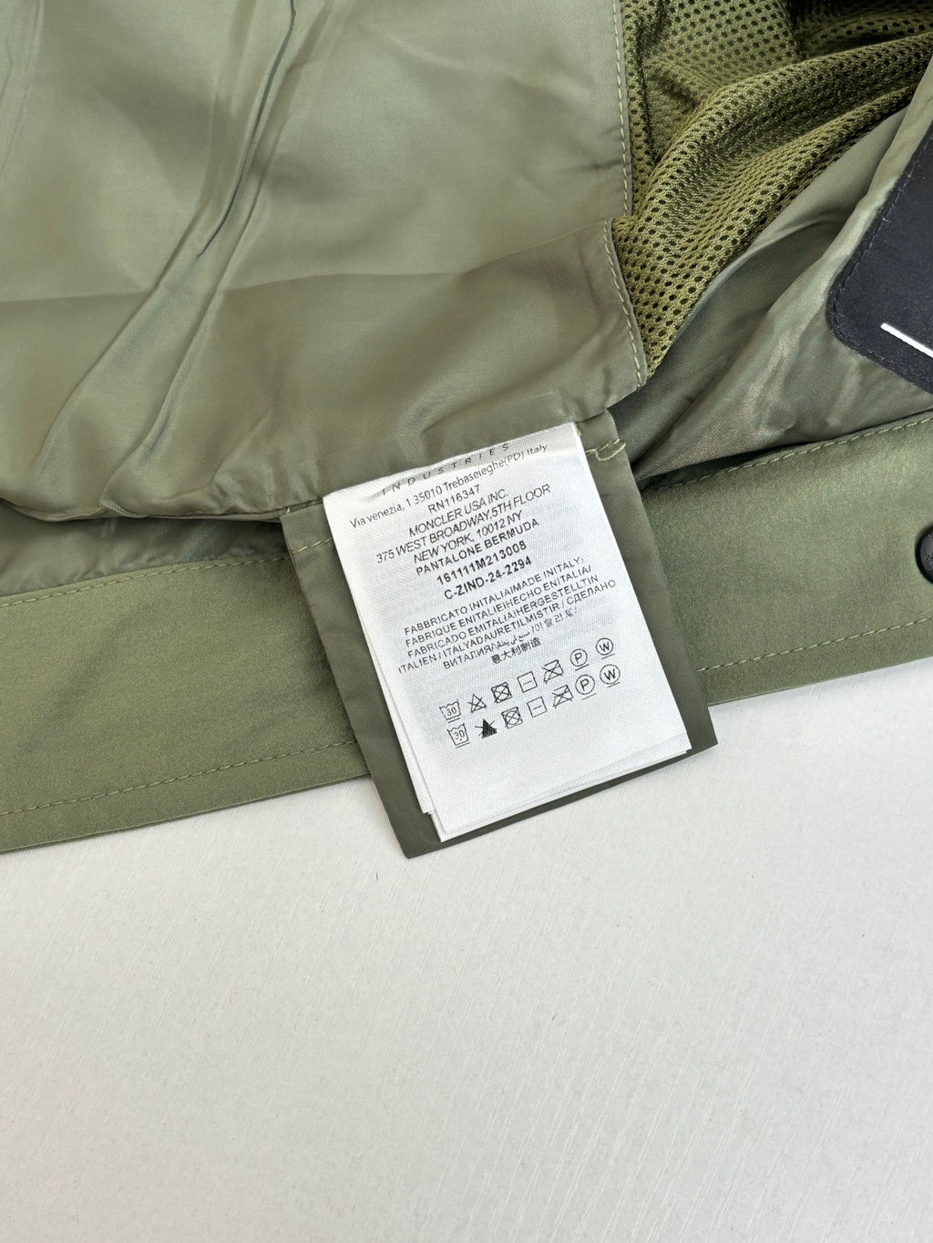 Long olive coat with care label and mesh lining near zipper