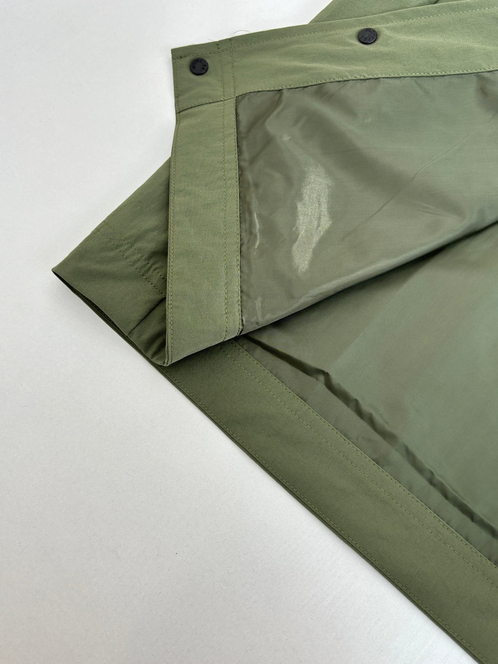 Long olive coat with angled side seam and snap button placket
