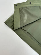 Long olive coat with angled side seam and snap button placket
