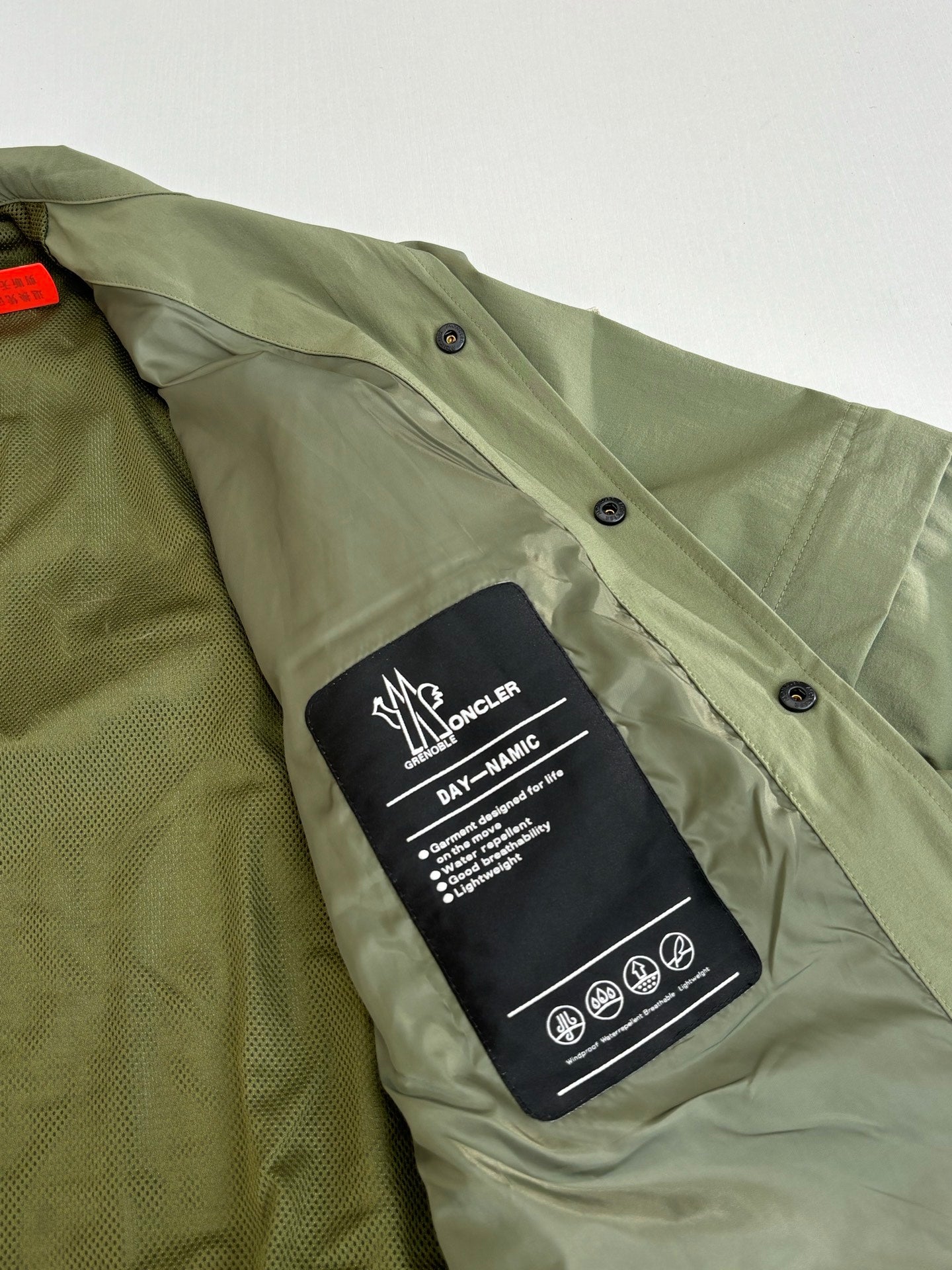 Moncler long jacket olive green with care label on button placket close-up