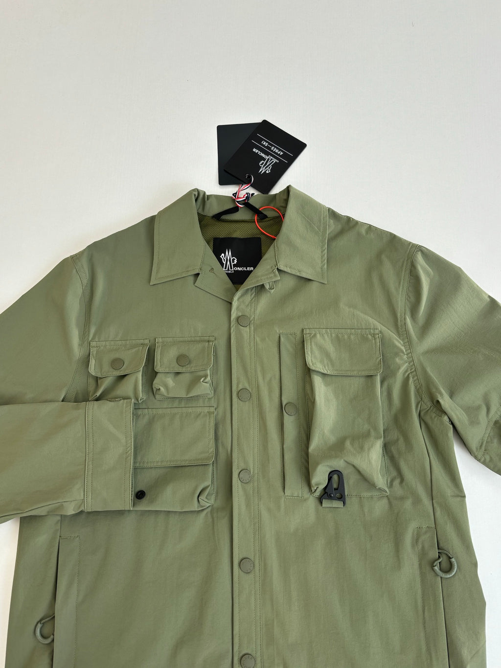 Moncler long jacket in olive green with chest pockets and buttoned placket close-up