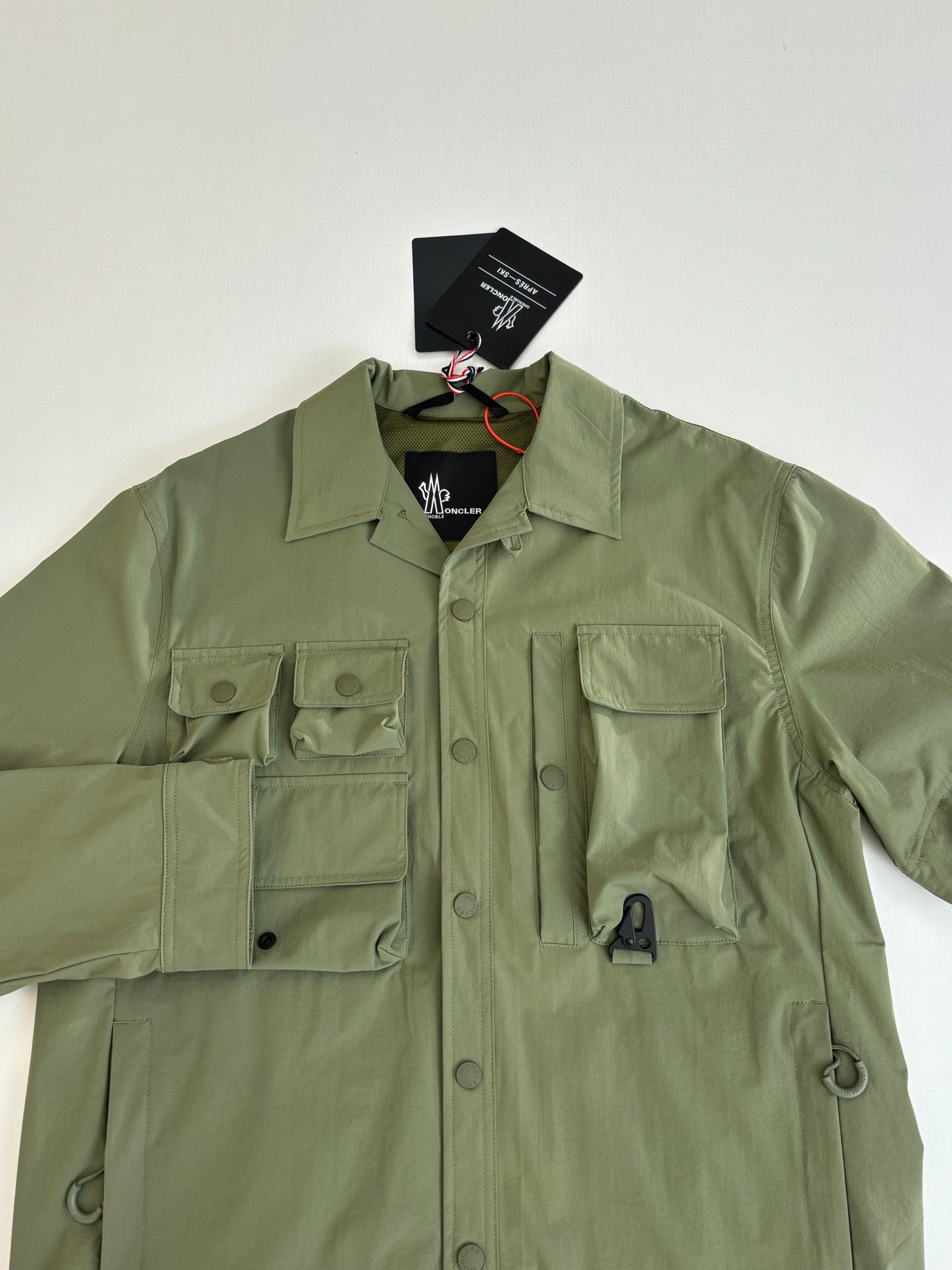 Moncler long jacket in olive green with chest pockets and buttoned placket close-up