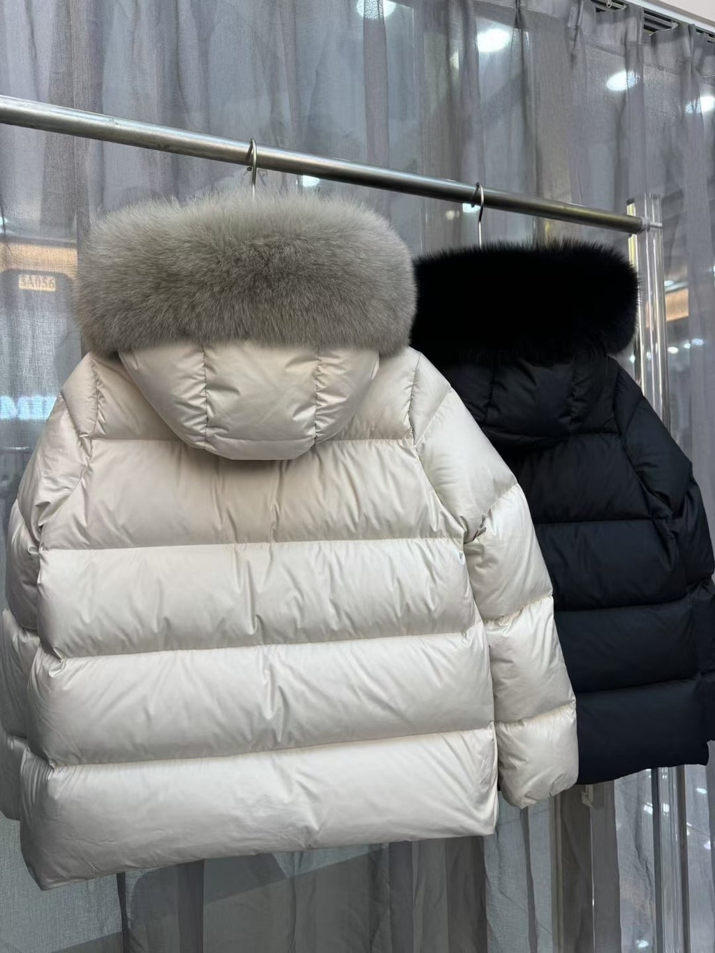 Moncler long puffer jackets, cream and black, fur-trimmed hoods (back view)