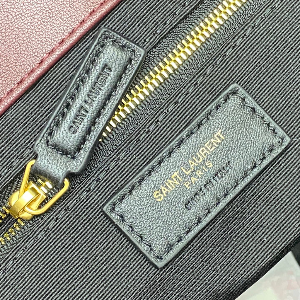 Maroon fabric label and gold zipper pull on quilted handbag interior pocket