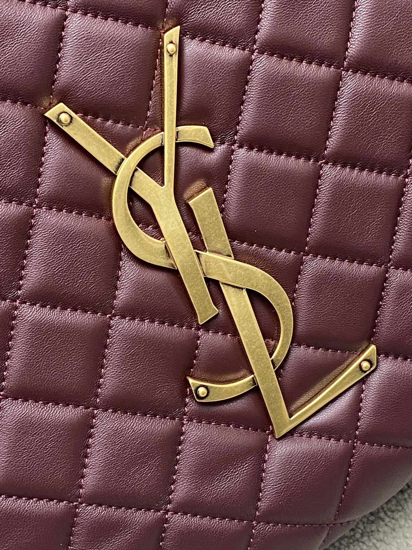 Gold YSL logo charm on maroon quilted handbag with diamond stitching texture