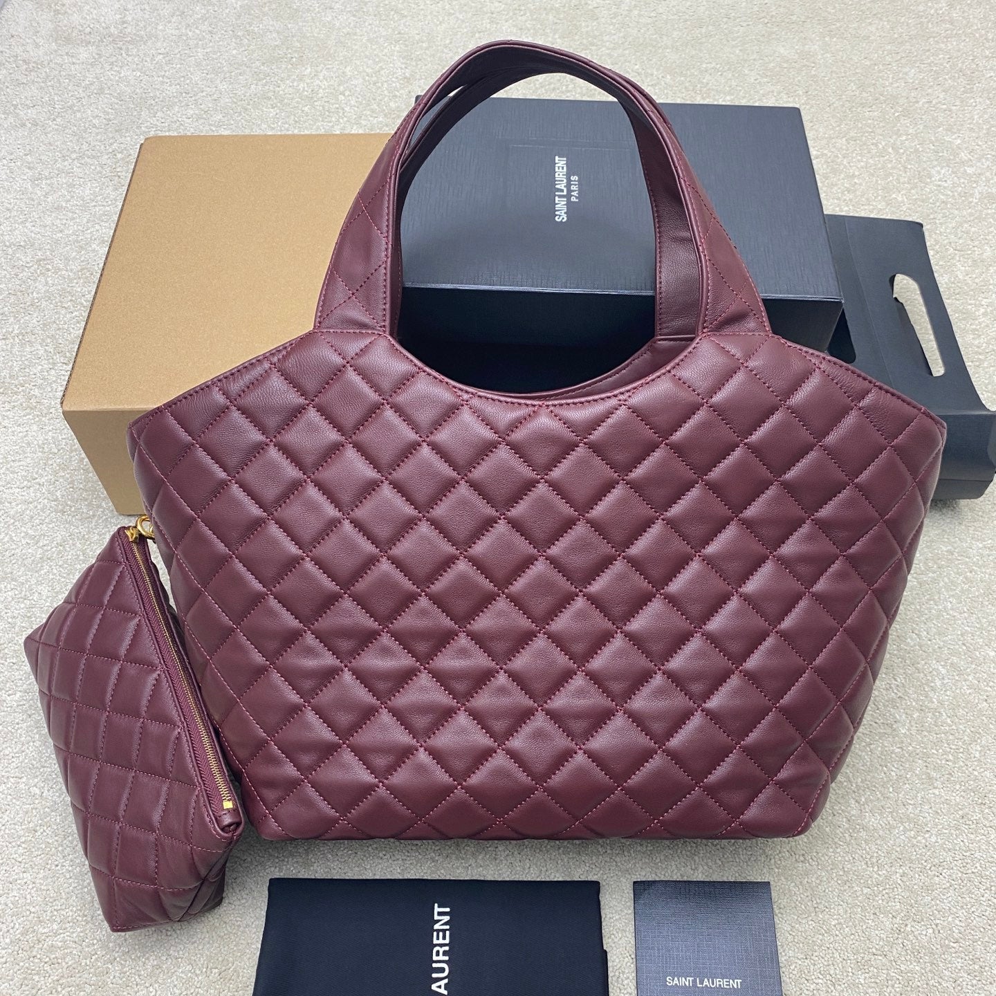 Quilted maroon tote-style handbag with YSL logo and side pouch with gold hardware