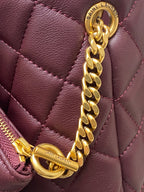 Maroon quilted handbag corner with gold chain strap and zipper pull detail