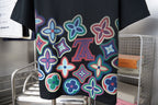 Black graphic T-shirt front with colorful flower print and centered LV motif