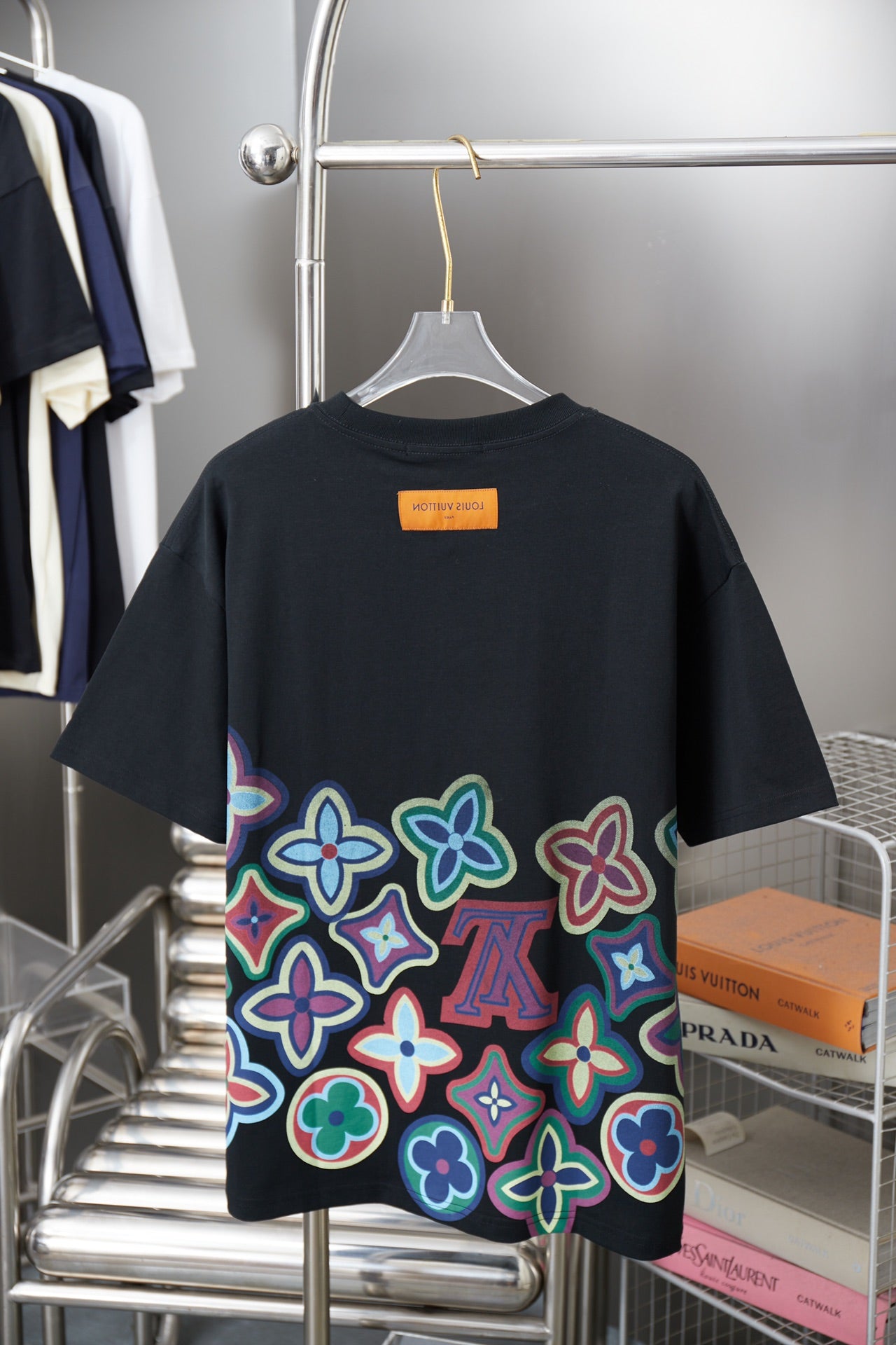Black graphic T-shirt back view with colorful flower print and orange brand label