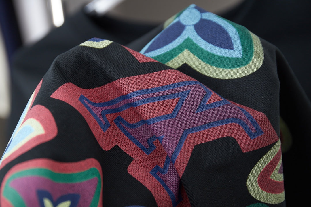 Black T-shirt with close-up multicolor abstract graphic overlay on sleeve