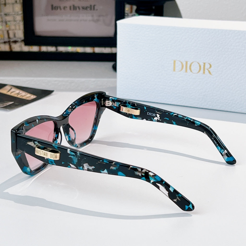 Dior sunglasses with teal patterned frame and pink tinted lenses, side view.