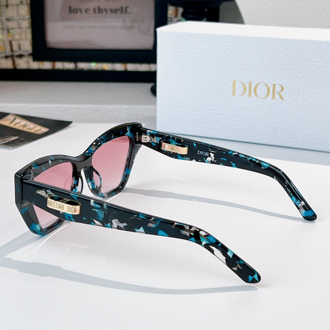 Dior sunglasses with teal patterned frame and pink tinted lenses, side view.