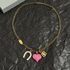 Gold-tone chain necklace with pink heart charm, horseshoe charm, and B pendant